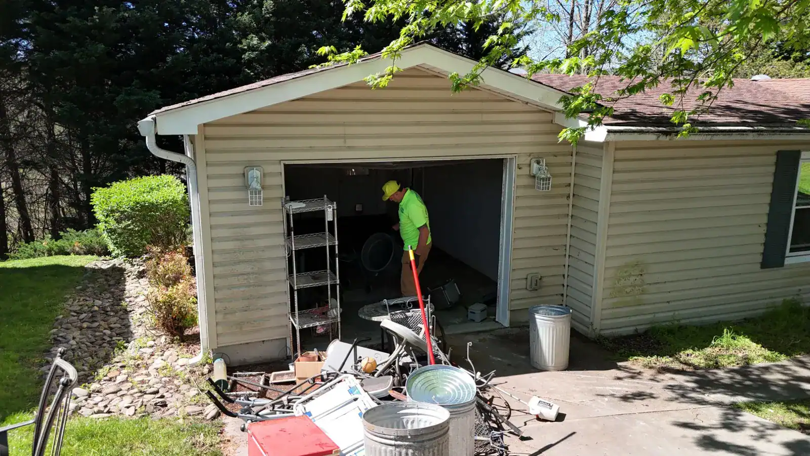 A garage packed with patio furniture, trash cans and old chairs before the cleanout