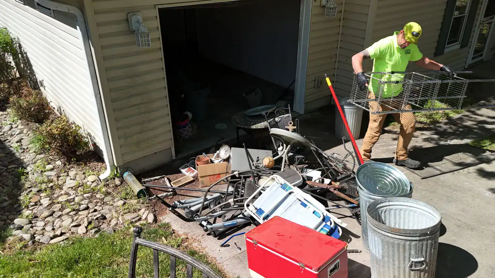 Two in One Junk Removal crew carrying wire shelving out of the garage